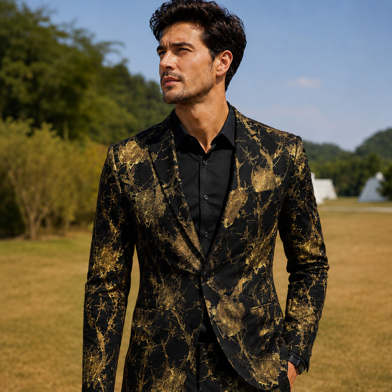 Close-up of a handsome man wearing a luxury black and gold floral printed blazer jacket outdoors.