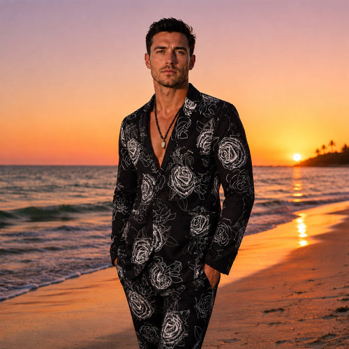 Slim fit men's black suit with white artistic rose print, worn on a beach at sunset.