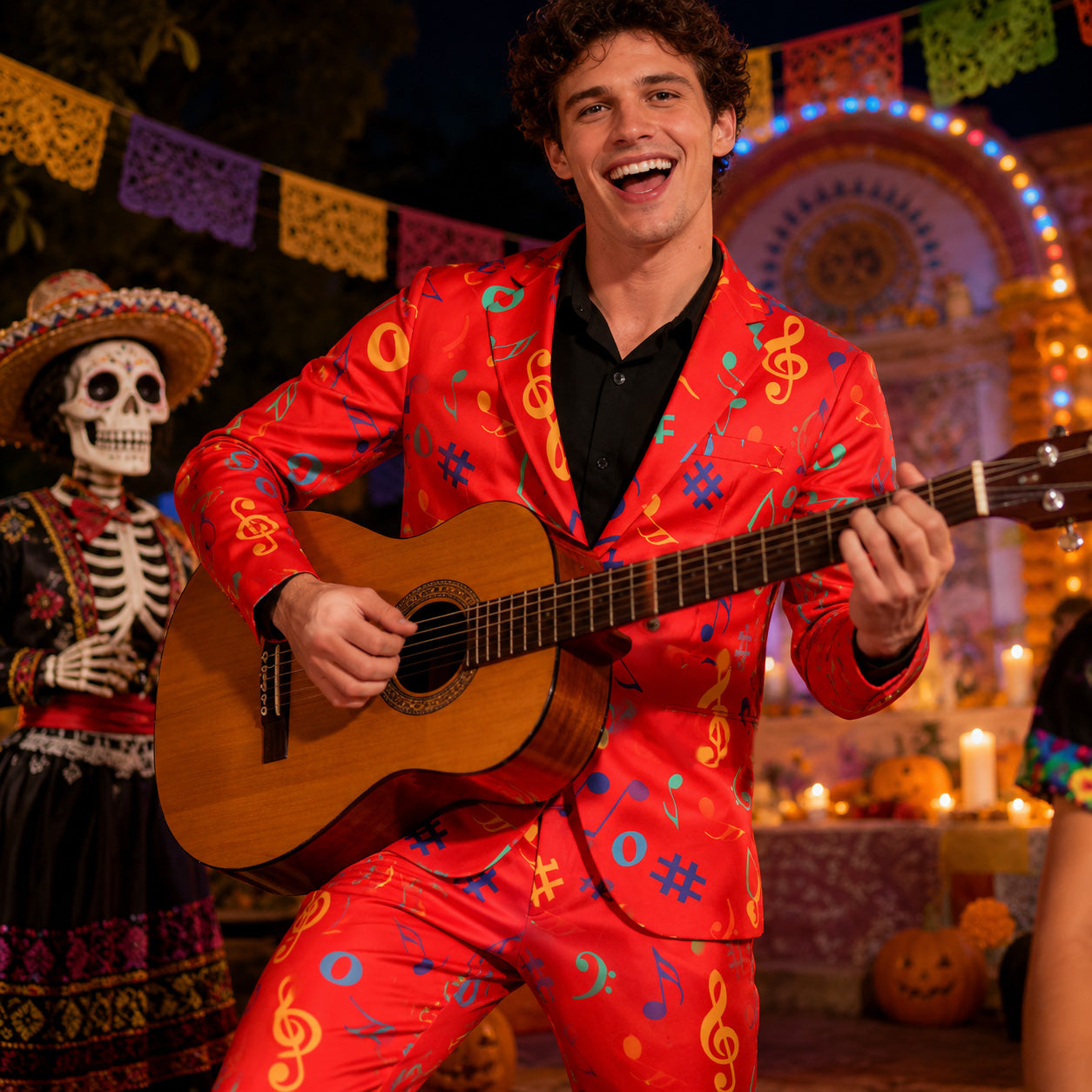 A cheerful man playing an acoustic guitar while wearing a Wisholic men's vibrant red suit printed with colorful music notes at a festive Day of the Dead celebration.