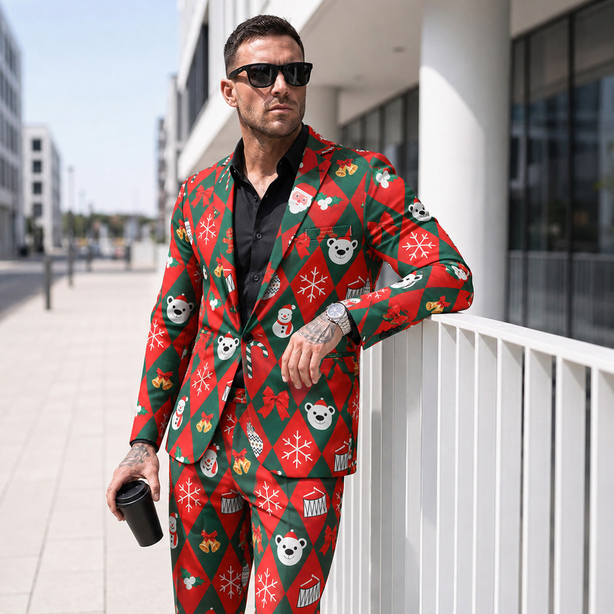 Stylish man wearing a 2-piece red and green holiday printed suit with dark sunglasses and coffee in an urban setting.