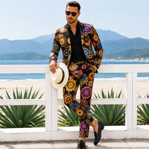 Front view of a tailored mens colorful patterned suit in a high-saturation geometric print, leaning on a white beachfront railing with a panama hat.
