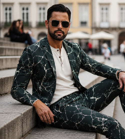 Wisholic luxury men's blazer featuring an artistic white crackle pattern on deep green fabric, paired with sunglasses and a cream henley shirt.