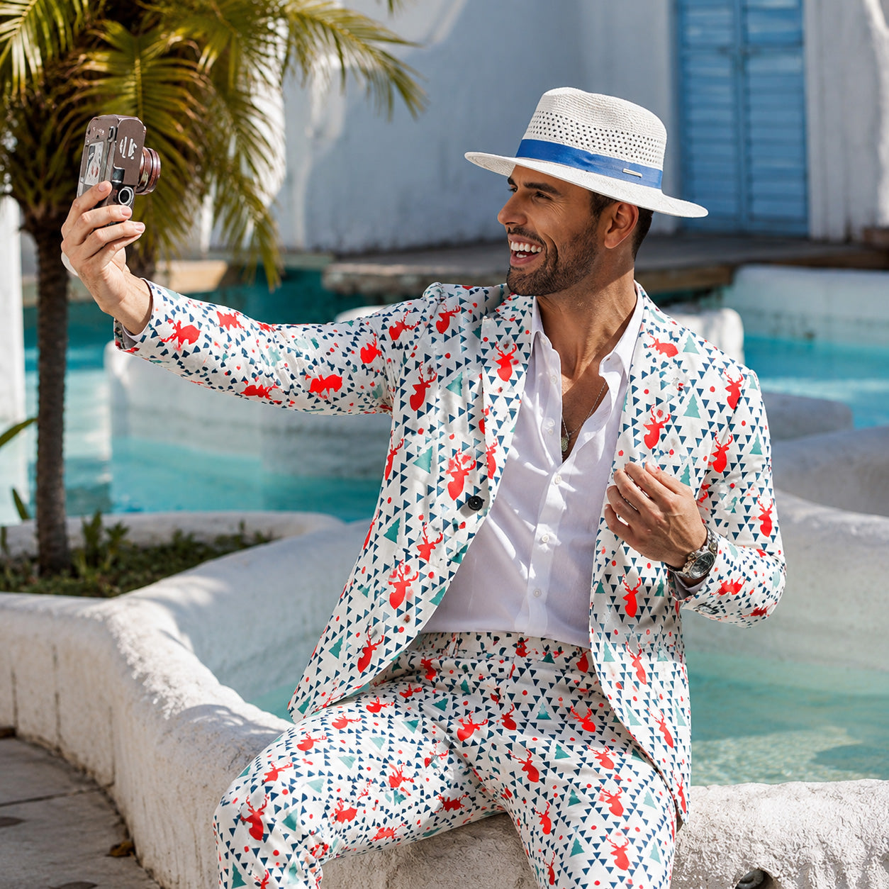Back view of WISHOLIC men's holiday printed suit featuring red reindeer pattern next to a decorated Christmas tree