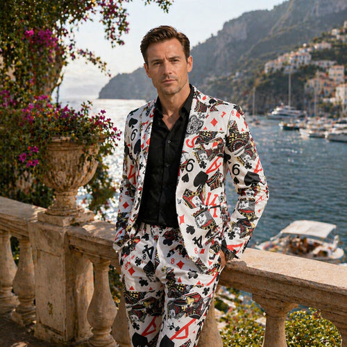 Man wearing Wisholic white suit with bold playing card prints, standing by a coastal balcony, perfect for casino nights.