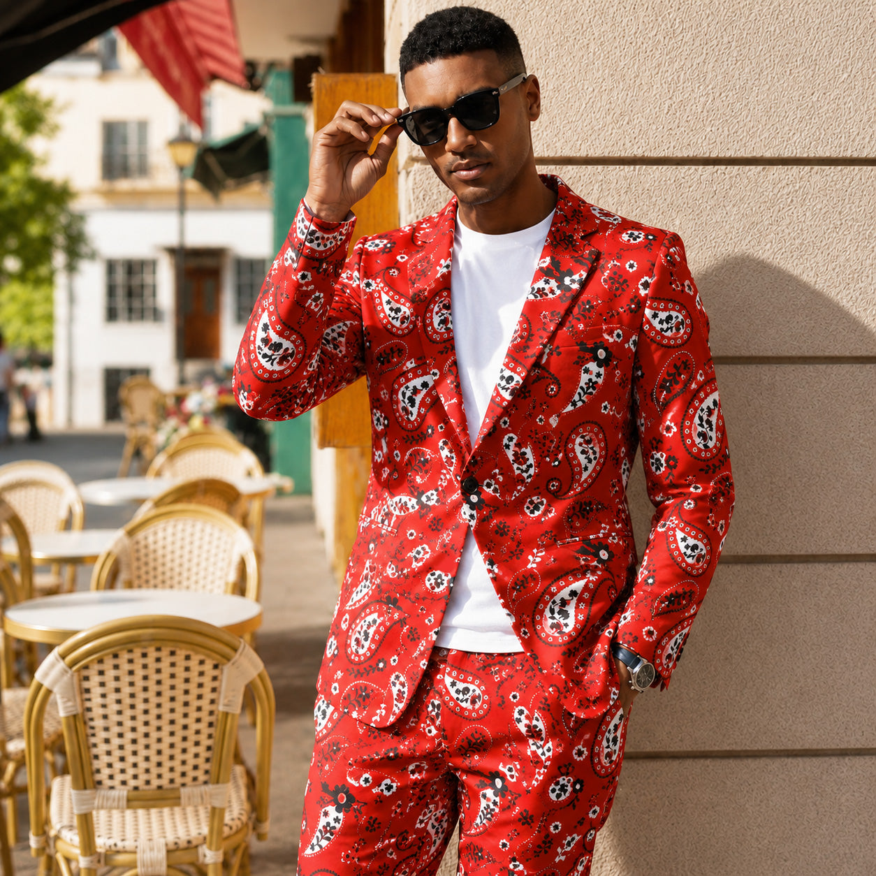 Man in Wisholic red paisley print suit and white t-shirt wearing sunglasses at an outdoor cafe.
